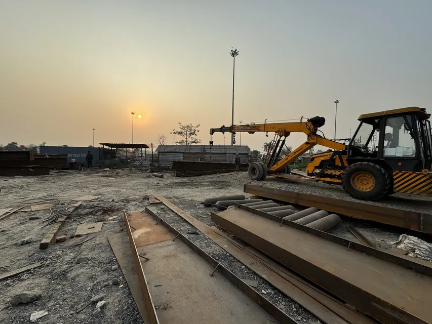 Fabrication yard with steel plates and heavy equipment at sunset