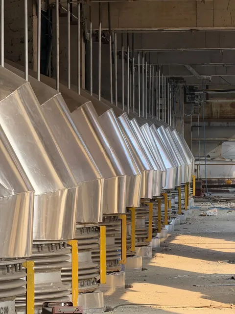 Row of steel chutes and hoppers inside a plant building