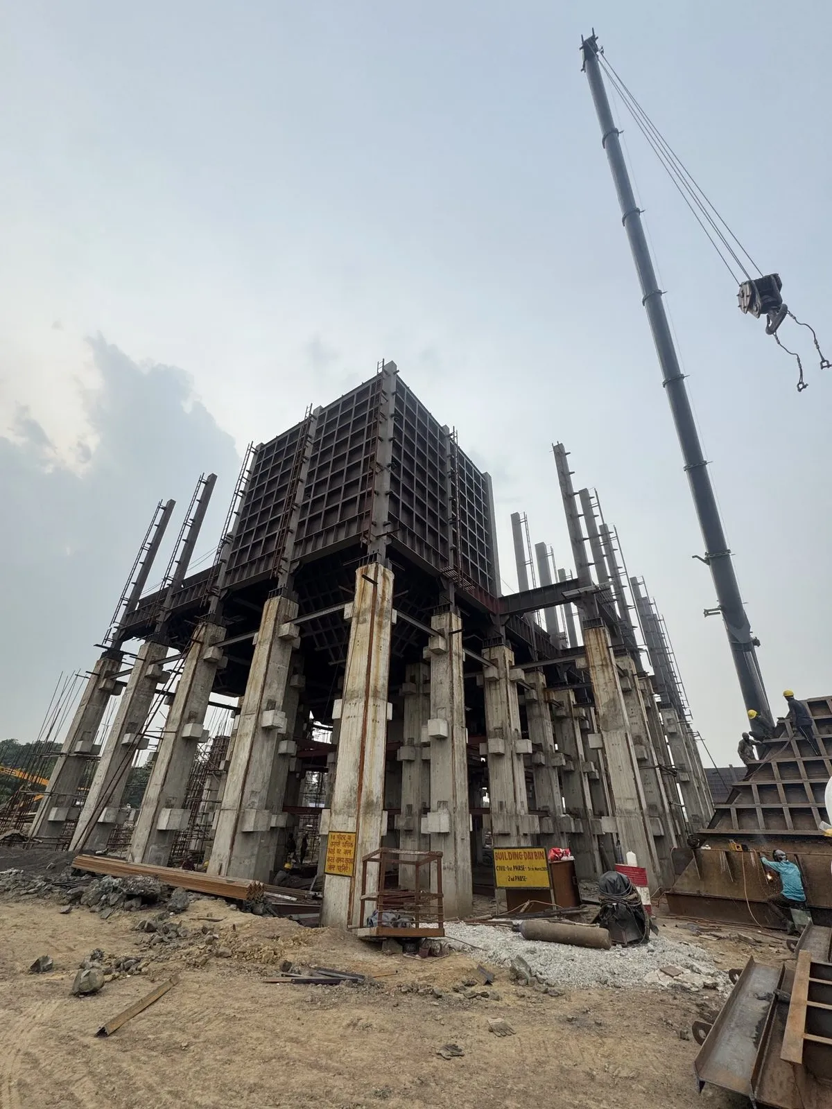 Tall steel structure under erection with a crane working alongside